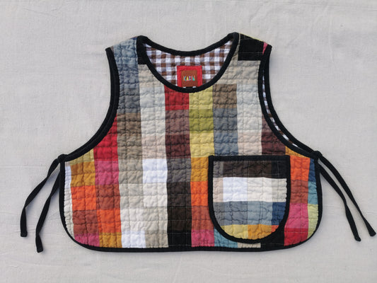 The front of a handmade colourful quilted patchwork linen vest by KABIN NZ with a patch pocket, brown gingham lining and black binding.